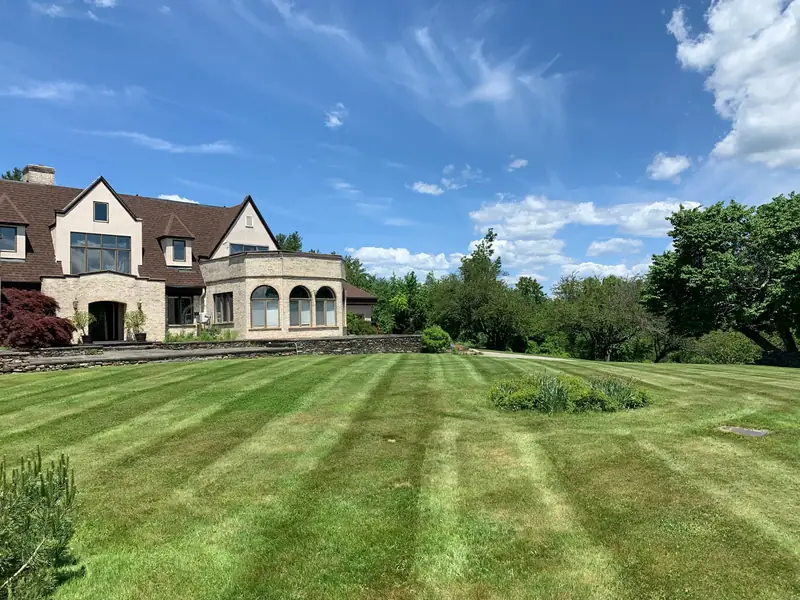 Freshly striped lawn in front of a large stone home