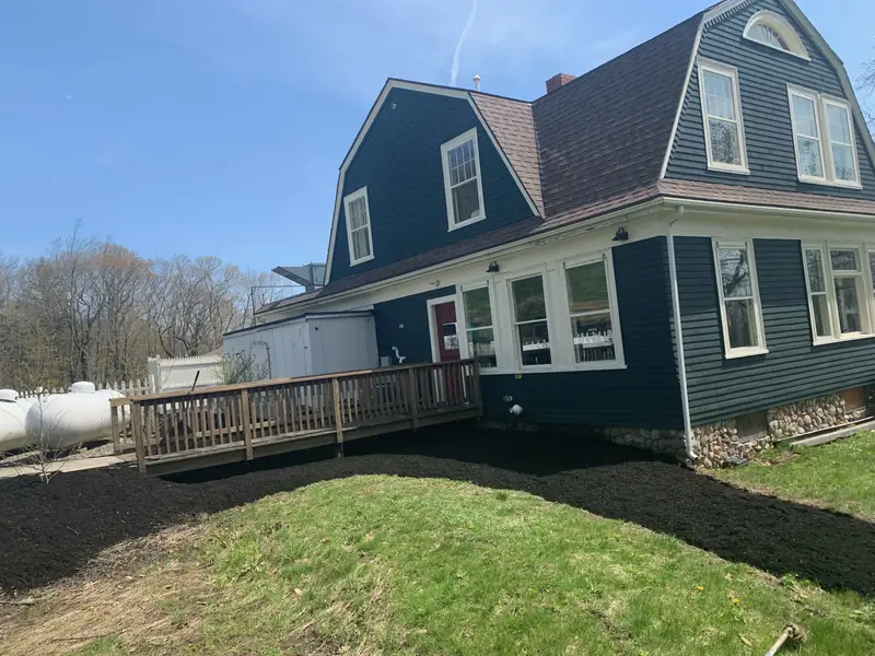 New lawn and mulch beds around a blue-gray home