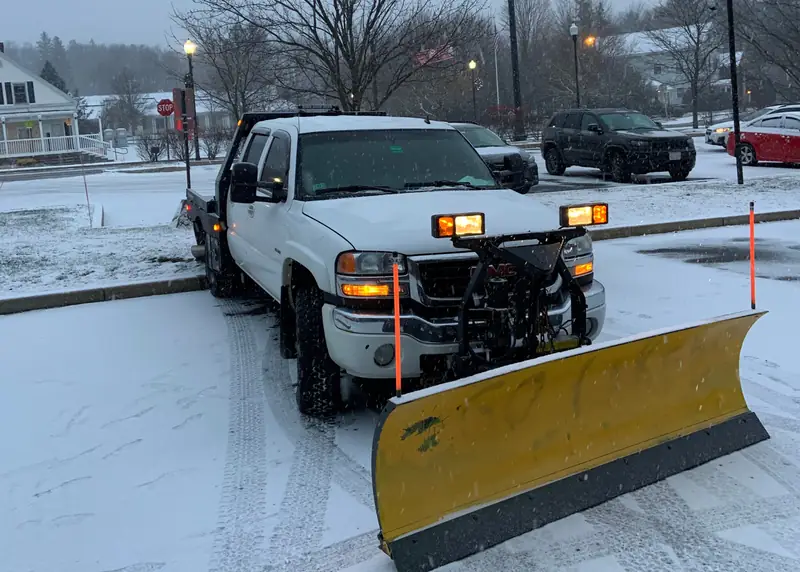 Plow truck clearing snow from a parking lot