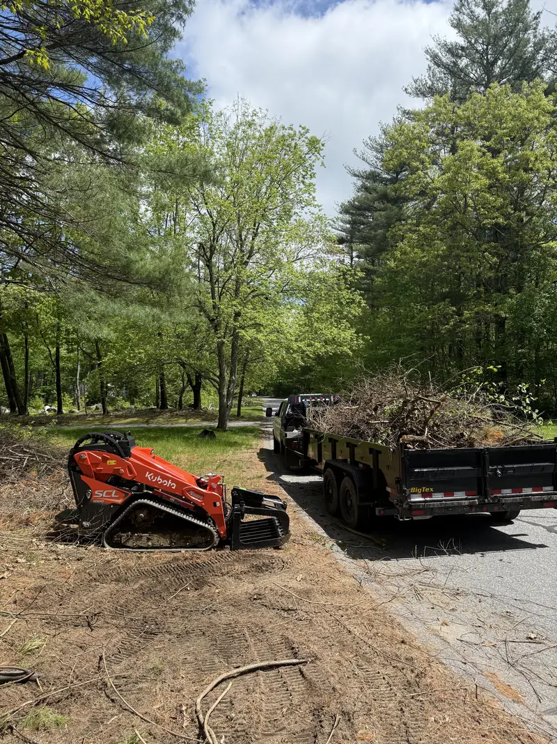 Compact track loader and dump trailer on a site work job
